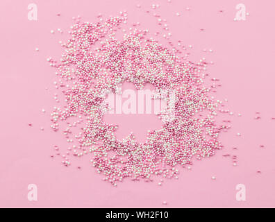 Rose et blanc sprinkles pearlized comestibles sur fond rose - rose nacré garniture gâteau fleur avec copie espace en vue de dessus sprinkles centre phot Banque D'Images