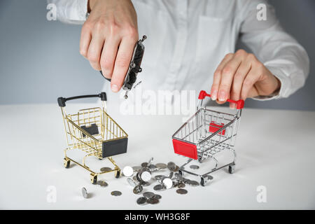 Main tenant une pièce de monnaie avec pile de pièce dans le panier sur fond gris et blanc. Banque D'Images