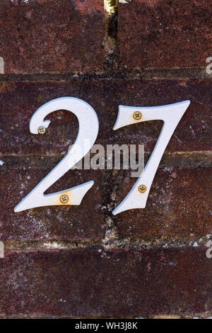 Maison blanche numéro 27 sur un vieux mur de brique Banque D'Images