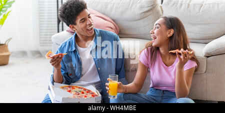 Heureux Couple Eating Pizza et de rire à la maison Banque D'Images