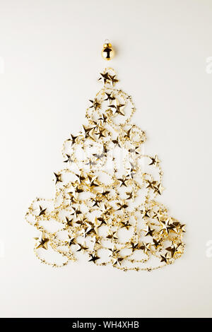 Création de Noël composition minimale.Nouvelle année symbole arbre de Noël de golden star garland sur fond blanc. Mise à plat, vue du dessus.Vertical ori Banque D'Images