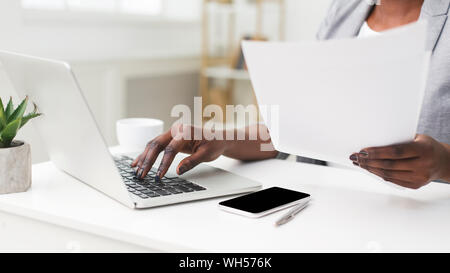 Dame d'affaires Working On Laptop Holding Papers au travail, Cropped Banque D'Images