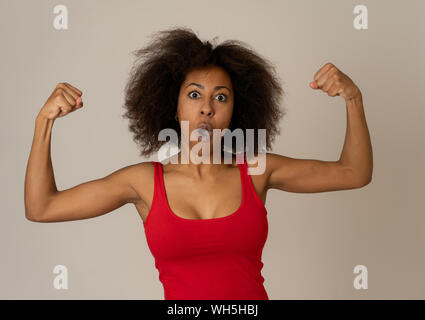 Portrait de jeune belle funny african american woman with afro hair style montrant les muscles des bras sourire fier d'avoir du plaisir. Dans les gens Succès et Hap Banque D'Images