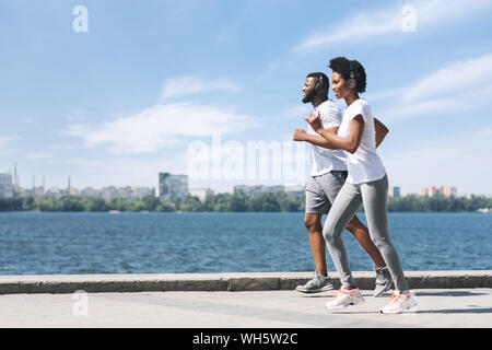 Black sportive Couple Jogging le long de la piscine du remblai Banque D'Images