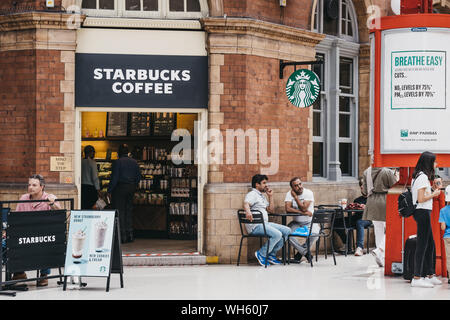 Londres, Royaume-Uni - 18 juillet 2019 : les gens aux tables de café Starbucks au sein de la station Marylebone, Londres. Starbucks est une chaîne de cafés américains célèbres. Banque D'Images