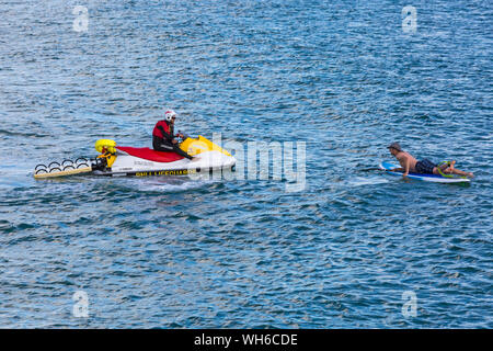 RNLI Lifeguard sur jetski en patrouille donnant des conseils à la paddle Boarder à la plage de Bournemouth pendant le Bournemouth Air Festival, Dorset UK en août Banque D'Images
