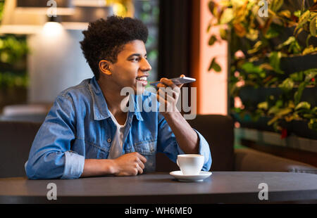 Young guy Enregistrer message vocal sur téléphone cellulaire Banque D'Images