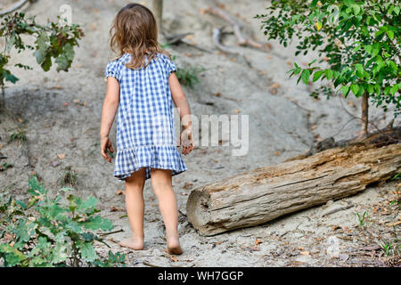 Vue arrière d'un enfant pieds nus dans une robe d'été fille marcher dans la forêt Banque D'Images