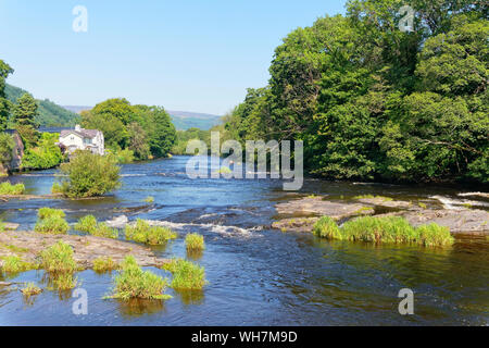 Un lumineux, hazyy, journée d'été à bas le courant rapide de la rivière bordée d'arbres, Dee à Llangollen, au Pays de Galles Banque D'Images