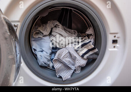 Lave-linge avec porte ouverte et les vêtements sales avant de les laver, linge plein de vêtements sales Banque D'Images