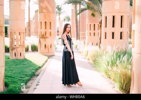 Young smiling woman in a black dress balade le long du front de mer Banque D'Images