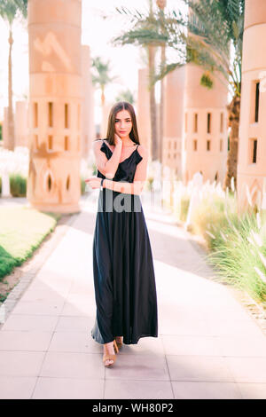 Young smiling woman in a black dress balade le long du front de mer Banque D'Images