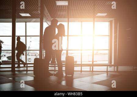 Photo de caresses l'homme et la femme debout à l'aéroport, effet de soleil Banque D'Images