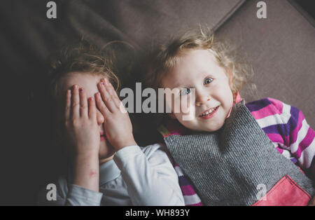 Portrait de deux petites sœurs lying on couch having fun, vue du dessus Banque D'Images