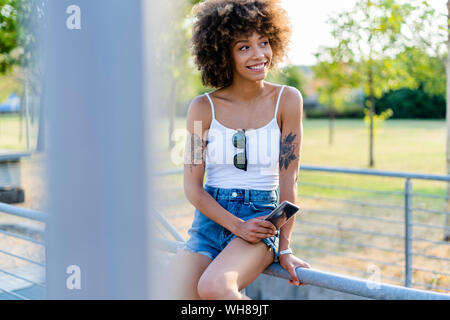 Portrait de jeune femme tatouée avec le smartphone en été Banque D'Images