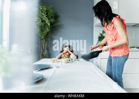 Mère servant repas pour fille assis à table à manger Banque D'Images