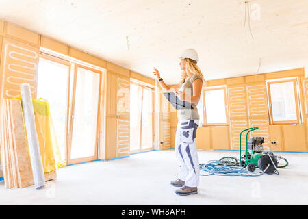 Jeune femme contrôle de la construction d'une nouvelle maison en bois Banque D'Images