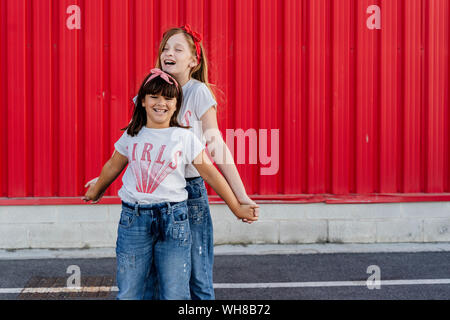 Sœurs debout devant un mur rouge Banque D'Images