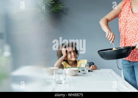 Mère servant repas pour fille assis à table à manger Banque D'Images