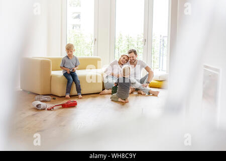 Famille heureuse avec deux fils jouant dans la salle de séjour de leur nouvelle maison Banque D'Images