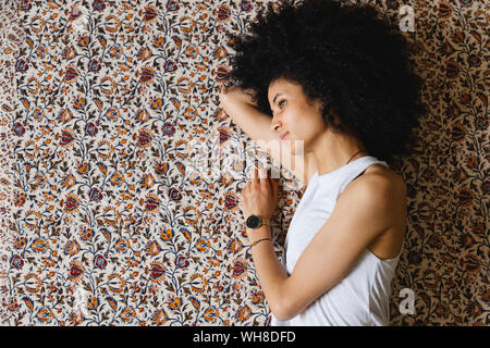Jeune femme couchée sur le côté sur le tapis Banque D'Images