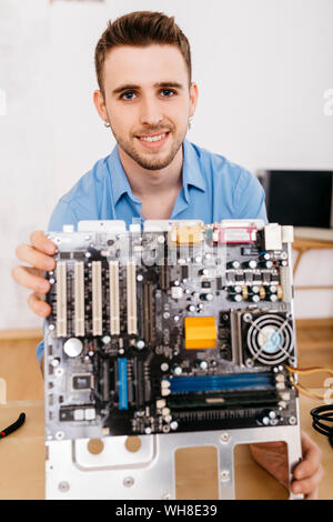 Portrait of smiling technician holding la carte mère d'un ordinateur Banque D'Images