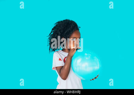 Petite fille devant un mur bleu, balloon Banque D'Images