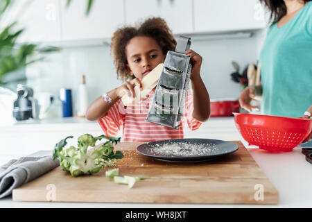 Cuisine fille avec la mère dans la cuisine au fromage râper Banque D'Images