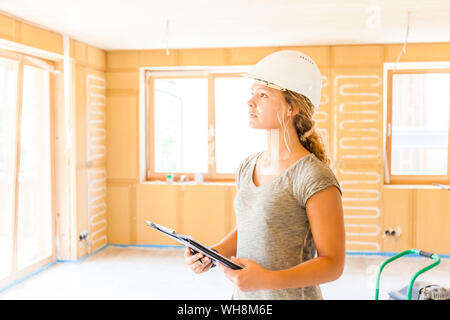 Jeune femme contrôle de la construction d'une nouvelle maison en bois Banque D'Images