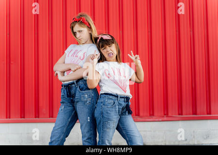Sœurs debout devant un mur rouge Banque D'Images