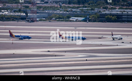 Un jet d'Alaska Airlines atterrit à l'aéroport international McCarran de Las Vegas (Nevada), les avions du sud-ouest et Delta attendre sur le tarmac. Banque D'Images