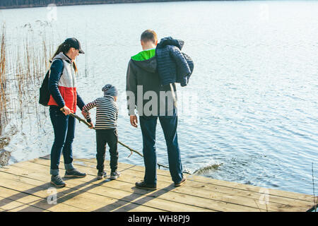 Père et Mère avec enfant Garçon jouant avec de l'eau banc près de Riverside. Banque D'Images