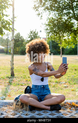 Portrait de jeune femme tatouée selfies en tenant avec le smartphone en été Banque D'Images