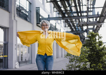 Portrait of smiling mature woman wearing cardigan jaune et foulard Banque D'Images