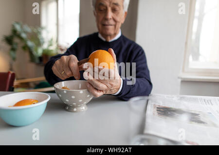 Man peeling orange at home Banque D'Images