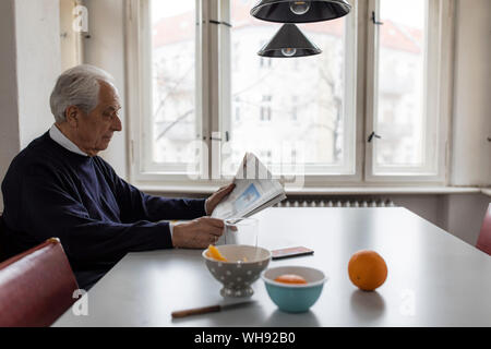 Senior man reading newspaper at home Banque D'Images