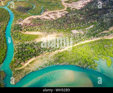 Vue aérienne de petit bateau arrivant à la mer par la rivière, entouré par une forêt dans le Queensland, Australie Banque D'Images