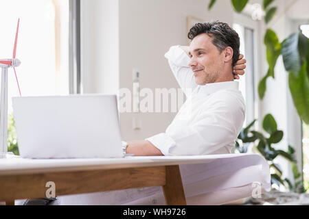 Businessma n assis dans office, en utilisant un ordinateur portable, à la recherche d'un modèle à windwheel Banque D'Images