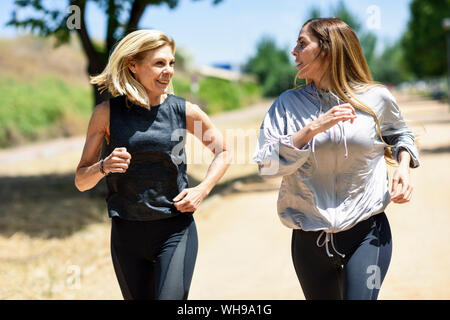 Young woman running avec sa fille dans un parc Banque D'Images