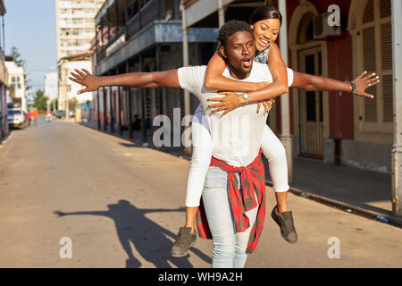 Young man carrying girlfriend piggyback dans la rue, Mabuto, au Mozambique Banque D'Images