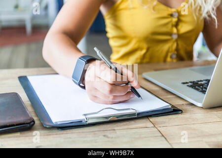 Woman writing on clipboard, close-up Banque D'Images