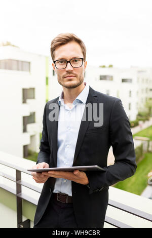 Portrait of a businessman with tablet debout sur un balcon dans une zone de développement Banque D'Images
