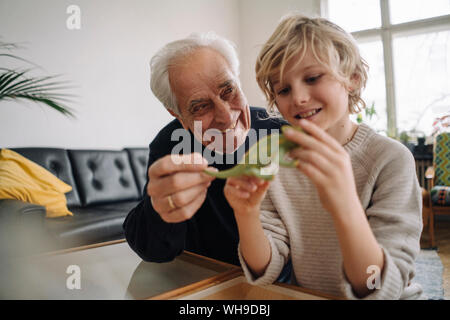 Heureux grand-père et petit-fils Playing with toy chameleon à la maison Banque D'Images