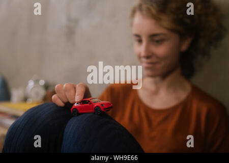 Jeune femme jouant avec petite voiture rouge Banque D'Images