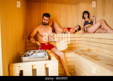 Les femmes et l'homme assis dans un sauna Banque D'Images