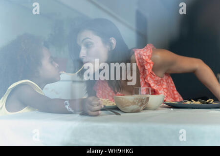 Mère et fille de manger à table à manger des pâtes spaghetti un partage Banque D'Images