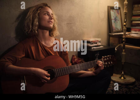 Jeune femme jouant de la guitare à la maison Banque D'Images
