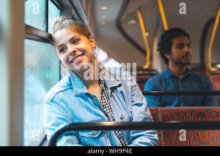 Portrait of happy young woman voyageant par autobus, London, UK Banque D'Images