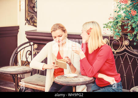 L'amélioration d'individu et de l'éducation. Discuter de librairie populaire. La littérature féminine. Réserver chaque fille devrait lire. Girls friends sitting café terrasse boire du café. Lecture livre inspirant. Banque D'Images