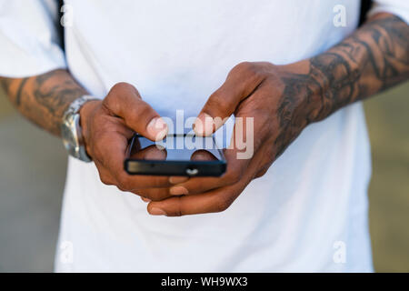 Mains de tattooed man using smartphone, close-up Banque D'Images